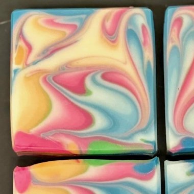 A bar of handmade soap swirled with pink, blue and gold