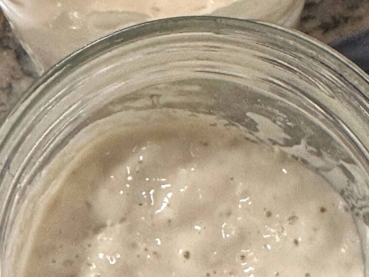 Active sourdough starter bubbling in an open glass jar